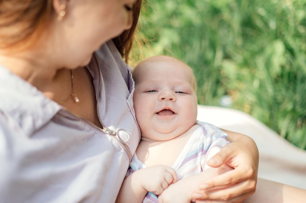 Szczęśliwa i uśmiechnięta mama z nowo narodzonym dzieckiem spędzająca czas w parku, ochrona przed słońcem dla dzieci i