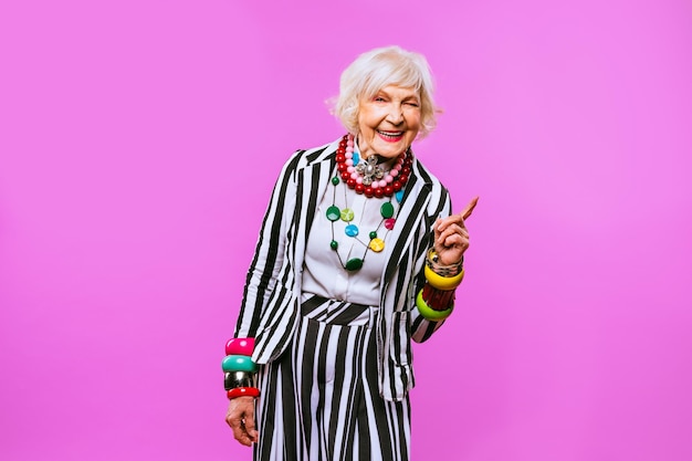 Szczęśliwa i zabawna fajna starsza pani z portretem modnych ubrań na kolorowym tle Młoda babcia z ekstrawaganckimi koncepcjami stylu dotyczącymi stażu życia i osób starszych