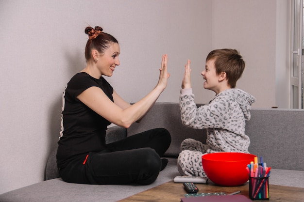 Szczęśliwa I Zabawna Mama Z Synem Klaszczą W Ręce Siedząc W Domu