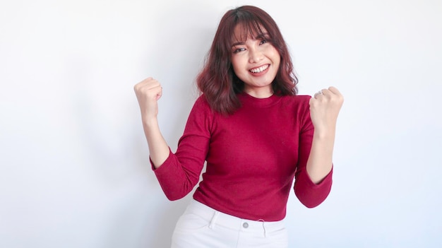 Szczęśliwa i zwycięzca Azjatycka piękna dziewczyna w czerwonej koszuli na białym tle