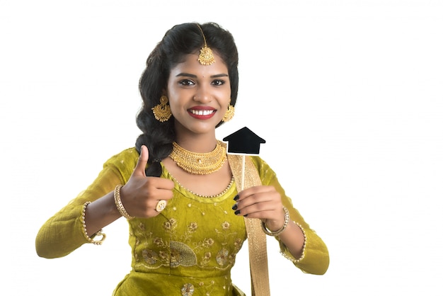 Szczęśliwa Indiańska Tradycyjna Młoda Kobieta Trzyma Troszkę Domową Wycinanki Deskę W Jej Rękach Na Białej ścianie.