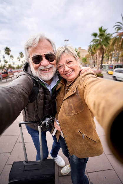 Szczęśliwa kaukazyjska para turystów robi razem selfie. Mąż i żona uśmiechają się do kamery.