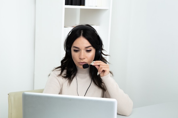 Szczęśliwa kobieta call center asystent siedzący przy biurku i wworking komputera wykonywanie różnych połączeń.