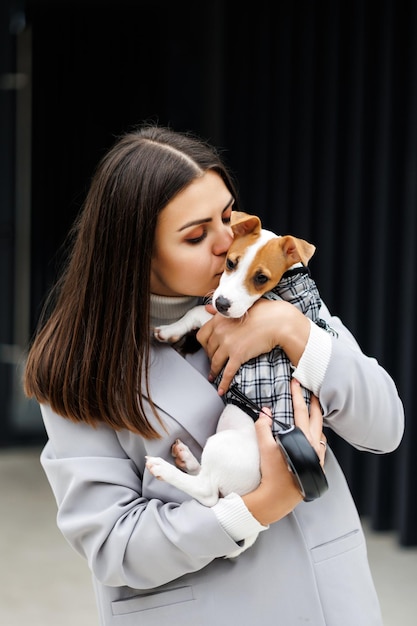 Szczęśliwa kobieta całuje się na ulicy ze swoim uroczym szczeniakiem Jack Russell Terrierem