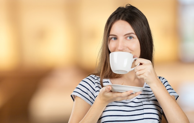 Szczęśliwa kobieta cieszy się ciepłą filiżankę herbata lub kawa na śniadanie