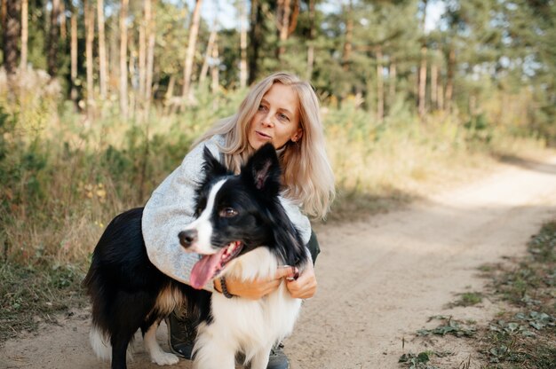 Szczęśliwa Kobieta I Czarno-biały Pies Rasy Border Collie W Lesie Jesienią