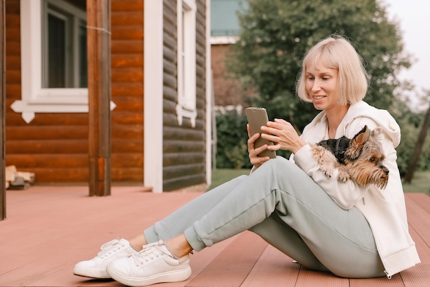 Szczęśliwa kobieta i pies yorkshire terrier podczas zabawy robią sobie portret selfie na smartfonie