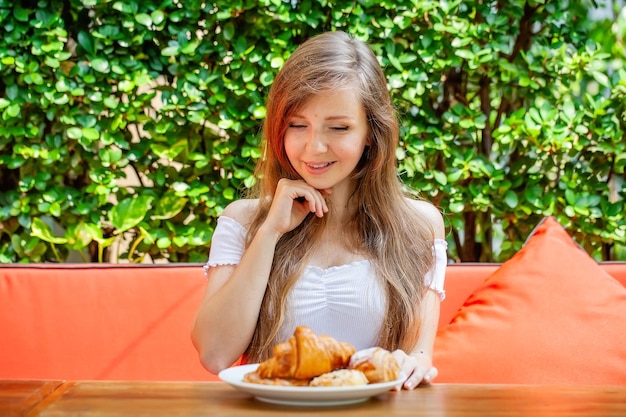 Szczęśliwa kobieta je słodkie śniadanie lub lunch w restauracji na świeżym powietrzu ze świeżym ciastem