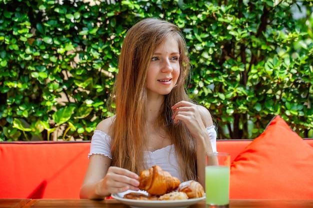 Szczęśliwa kobieta je słodkie śniadanie lub lunch w restauracji na świeżym powietrzu ze świeżym ciastem