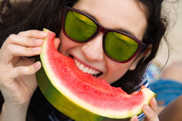 Szczęśliwa kobieta jedząca arbuz na plaży