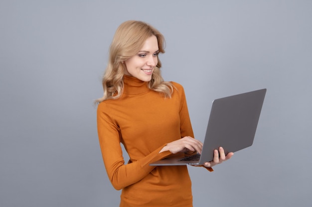 Szczęśliwa kobieta korzysta z nowoczesnej technologii laptopów na szarym tle surfowania po internecie
