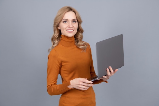 Szczęśliwa kobieta korzysta z przenośnego komputera osobistego przeglądającego online szare tło laptopa