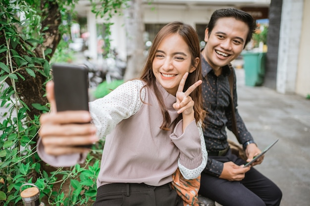 Szczęśliwa kobieta korzystająca ze smartfona biorąca selfie i wideorozmowę ze swoim partnerem
