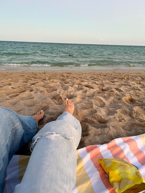 Szczęśliwa kobieta korzystających z pięknego zachodu słońca na plaży Nogi przeznaczone do walki radioelektronicznej na piasku