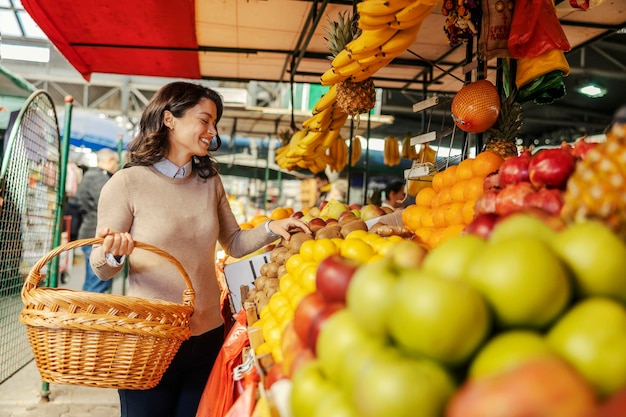 Zdjęcie szczęśliwa kobieta kupuje owoce na targu rolniczym