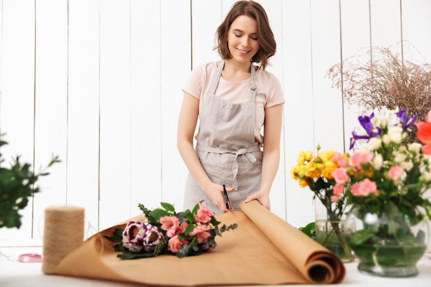 Szczęśliwa kobieta kwiaciarnia pracuje z kwiatami w warsztacie.
