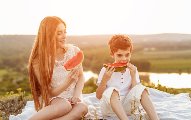 Szczęśliwa kobieta nastolatek i ładny braciszek razem siedząc na pikniku