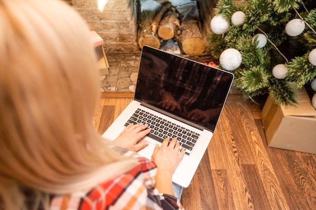 Zdjęcie szczęśliwa kobieta patrząca na laptopa przed choinką