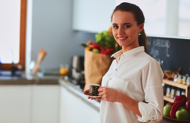 Szczęśliwa kobieta pijąca herbatę w kuchni w domu