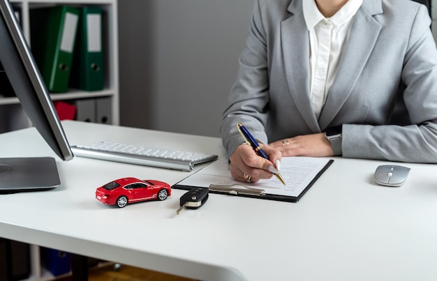 Zdjęcie szczęśliwa kobieta podpisuje umowę pożyczki, kupuje nowy samochód lub wynajmuje pojazd w biurze