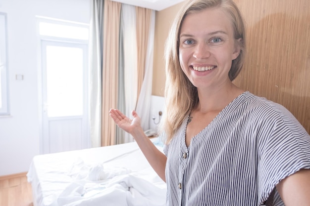 Szczęśliwa kobieta pokazująca swój pokój hotelowy i robiąca selfie