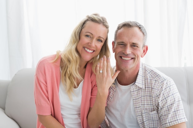 Szczęśliwa kobieta pokazuje pierścionek zaręczynowego oprócz mężczyzna