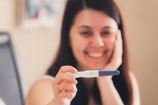 Szczęśliwa kobieta pokazuje pozytywny test ciąży z bliska
