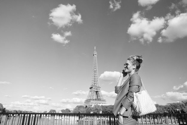 Szczęśliwa kobieta przy moście na rzece na wieży Eiffla w Paryżu, Francja Podróżując na letnie wakacje Dziewczyna o modnym wyglądzie i zmysłowej urodzie Marzy o Paryżu Uśmiech kobiety w okularach przeciwsłonecznych na błękitnym niebie