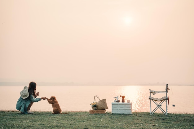 Zdjęcie szczęśliwa kobieta relaksuje się z psem w wakacyjny poranek podróżując i spoczynkowym stylem slow life camping selektywna i miękka ostrość