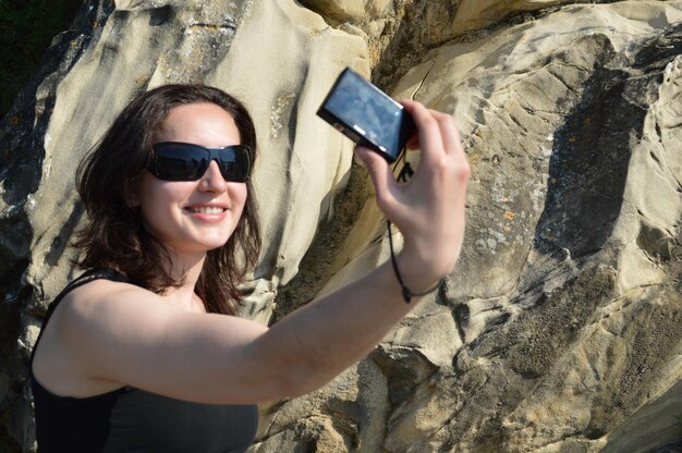 Szczęśliwa kobieta robiąca selfie z kamery przeciwko formacji skalnej