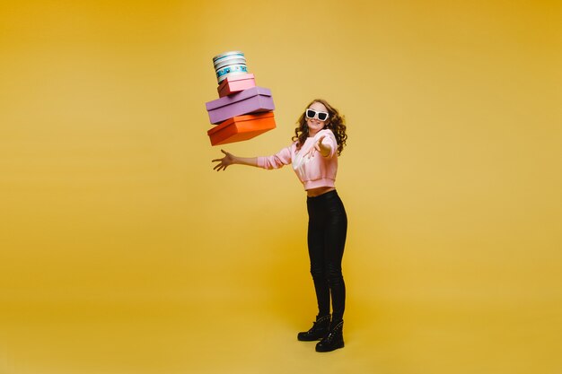 Szczęśliwa kobieta rzuca kolorowe papierowe pudełka po zakupach