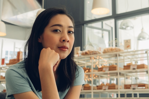 Szczęśliwa kobieta siedzi i czeka na kogoś w kawiarni piekarni.
