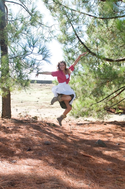 szczęśliwa kobieta skacząca wśród sosen