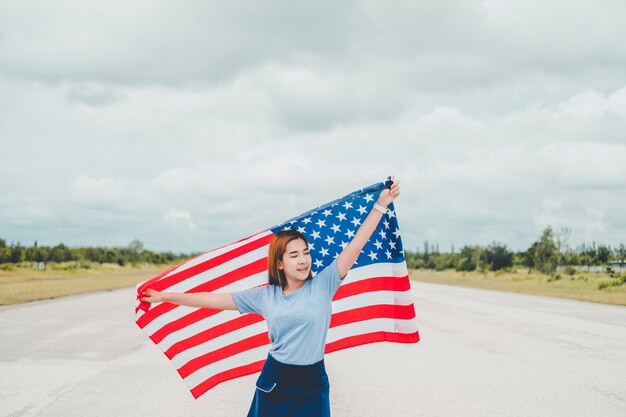 Szczęśliwa kobieta stojąca z amerykańską flagą Patriotyczne wakacje. USA świętują 4 lipca