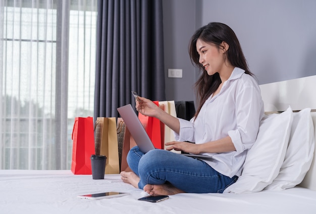 Szczęśliwa Kobieta Używa Laptop Dla Online Zakupy Z Kredytową Kartą Na łóżku