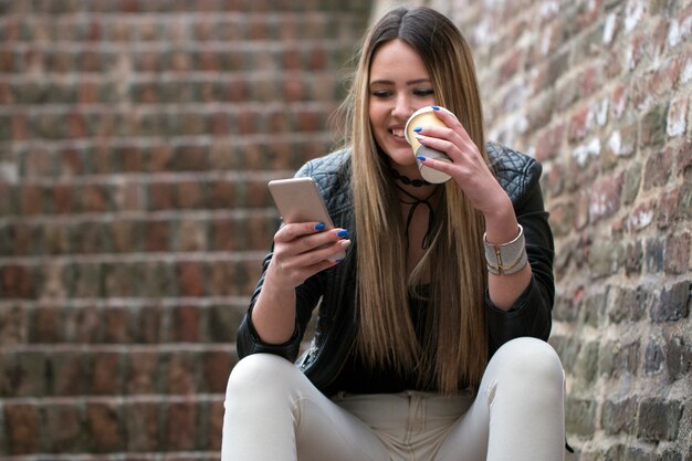 Szczęśliwa kobieta używa mądrze telefon w ulicie