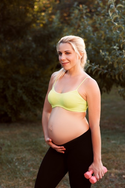 Szczęśliwa kobieta w ciąży czuje, jak jej dziecko naciska na fitness.