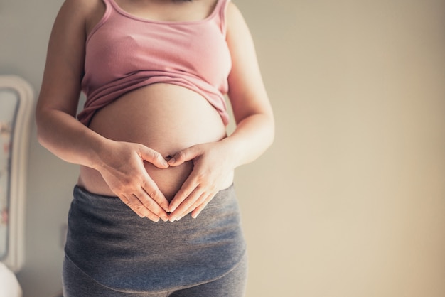 Szczęśliwa kobieta w ciąży z dzieckiem w ciąży brzuch. Opieka prenatalna i ciąża położnicza.