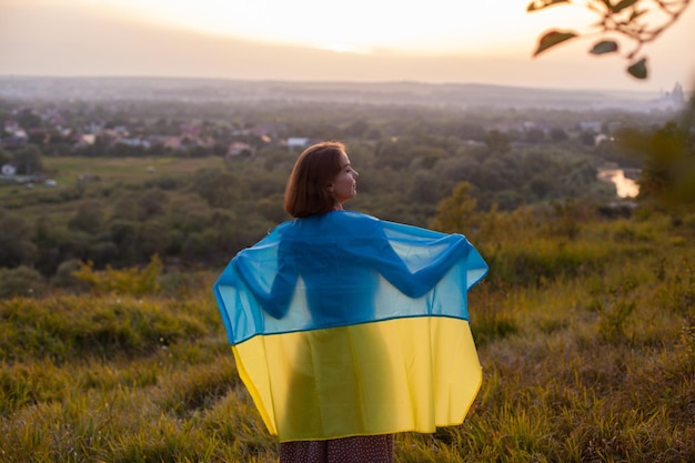 Szczęśliwa kobieta w długiej sukni trzymająca żółto-niebieską flagę Ukrainy