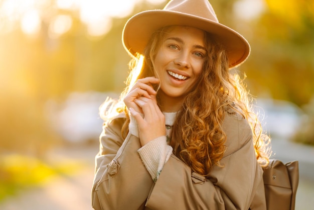 Szczęśliwa kobieta w stylowym swetrze i kapeluszu na świeżym powietrzu w jesiennym parku w kratę Kobieta lubi jesienną przyrodę
