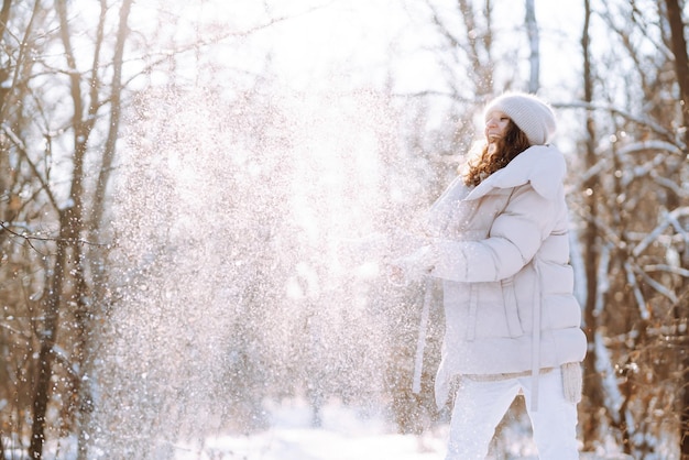 Szczęśliwa kobieta w ubraniach w stylu zimowym spacerująca w zaśnieżonym parku Koncepcja podróży wakacje natura