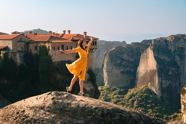 Szczęśliwa kobieta w żółtej sukience podróżnik meteora klasztor na tle