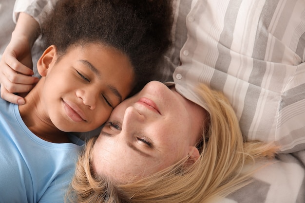 Szczęśliwa kobieta z jej córką African-American, leżąc na łóżku