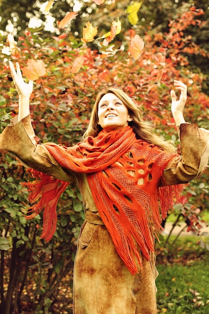 Zdjęcie szczęśliwa kobieta z jesiennymi liśćmi w jesiennym parku