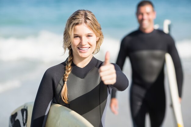 Szczęśliwa kobieta z surfboard pokazuje jej kciuk up