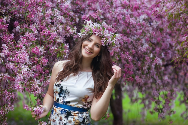 Szczęśliwa kobieta z wiankiem na jego głowie w kwitnie wiosna ogródzie