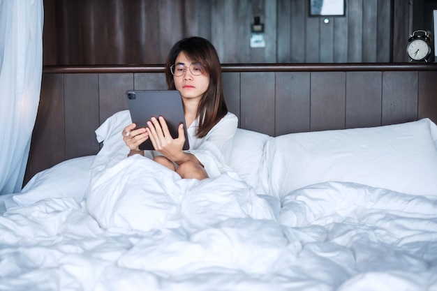 Szczęśliwa kobieta za pomocą tabletu do mediów społecznościowych młoda kobieta ogląda filmy na komputerze pad na łóżku w domu sieć technologia zakupy online e-commerce styl życia i koncepcja komunikacji cyfrowej