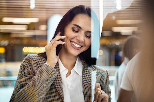 Szczęśliwa kobieta zakupoholiczka uśmiechnięta rozmowa używa smartfona w nowoczesnym centrum handlowym weekendowy wypoczynek