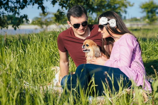 Szczęśliwa kochająca młoda para spędzająca czas w parku, siedząca na zielonym trawniku w słoneczny letni dzień