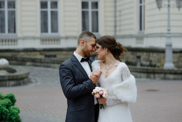 Szczęśliwa luksusowa ślub para całuje i obejmuje blisko retro z bukieta samochodem w jesieni